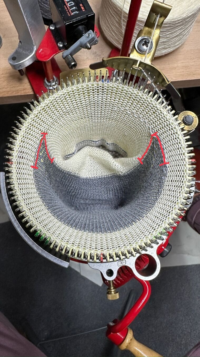 Finished gray heel and already a few foot rounds in white yarn worked over it. The additional rows (decreases and increases) are marked in red.