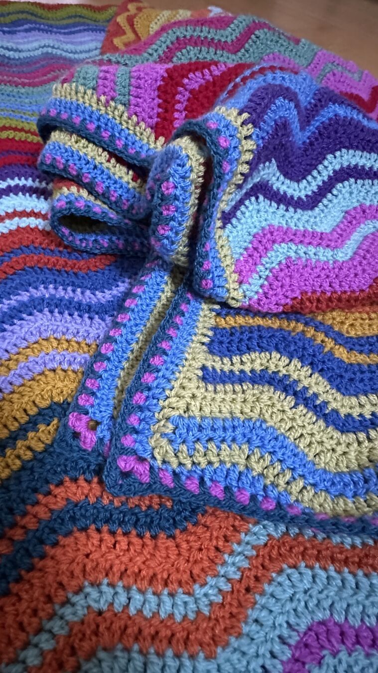 The same blanket, not as neatly folded, more crumpled up.
The four round border is better visible now, colors are pistachio green, aster blue, magenta and petrol.